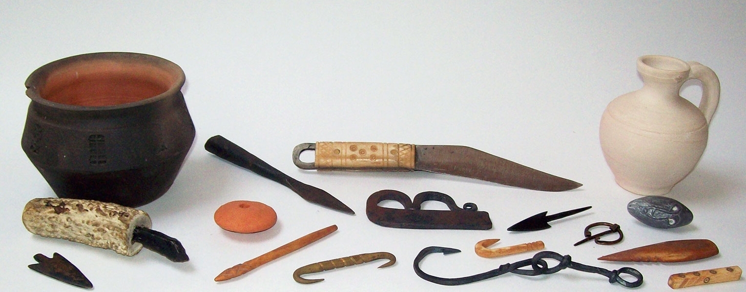 Stilleven met replica’s van historische voorwerpen, waaronder aardewerk en metalen gereedschap.